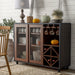 Left-angled vintage walnut wine bar cabinet in a country farmhouse style dining room. A lamp and decorative pumpkins sit on the tabletop. Behind the wire mesh cabinet doors are cups and plates. Orange wine glasses hang on stemware racks while wine bottles are stored in the wine rack.