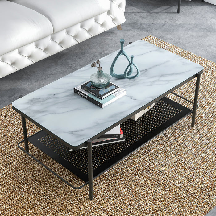 Right angled top-down modern industrial black steel coffee table with tempered white marble glass top, slender steel legs and perforated open metal shelf with decor on a rug in front of a sofa.