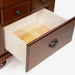 Detail shot of the bottom drawer of a traditional cherry nightstand against a white background. It features a ring pull.