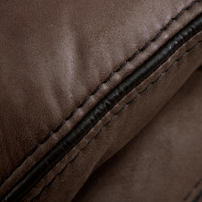 Right facing close up of the stitching of a transitional brown microfiber reclining sofa with accent stitching on a white background