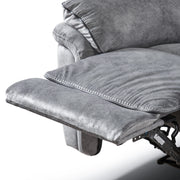 Left facing close up of the raised leg rest of a transitional grey microfiber sofa with accent piping on a white background