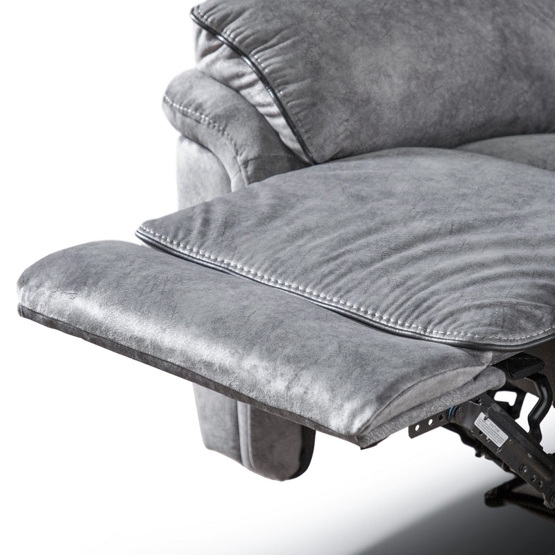 Left facing close up of the raised leg rest of a transitional grey microfiber sofa with accent piping on a white background