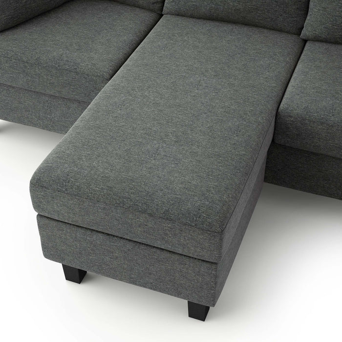 Left facing close up of the ottoman of a transitional dark grey customizable sectional sofa on a white background