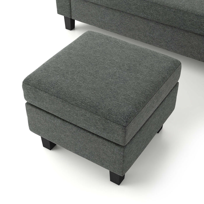 Left facing close up of the detached ottoman of a transitional dark grey customizable sectional sofa on a white background