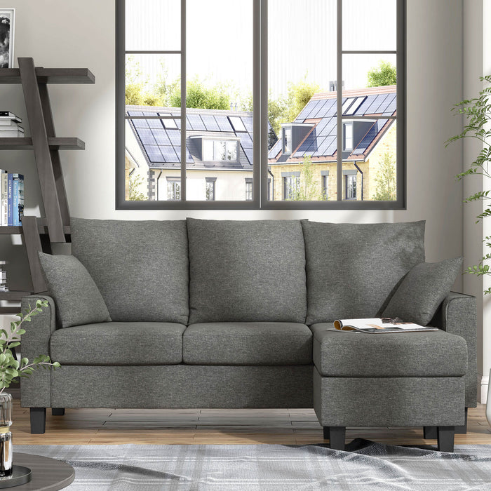 Front facing contemporary grey sectional sofa with an adjustable ottoman in a living room with accessories