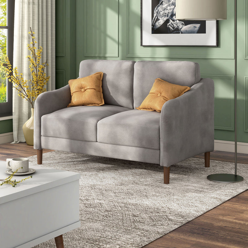 Left facing modern grey velvet loveseat with sloping arms in a room with accessories