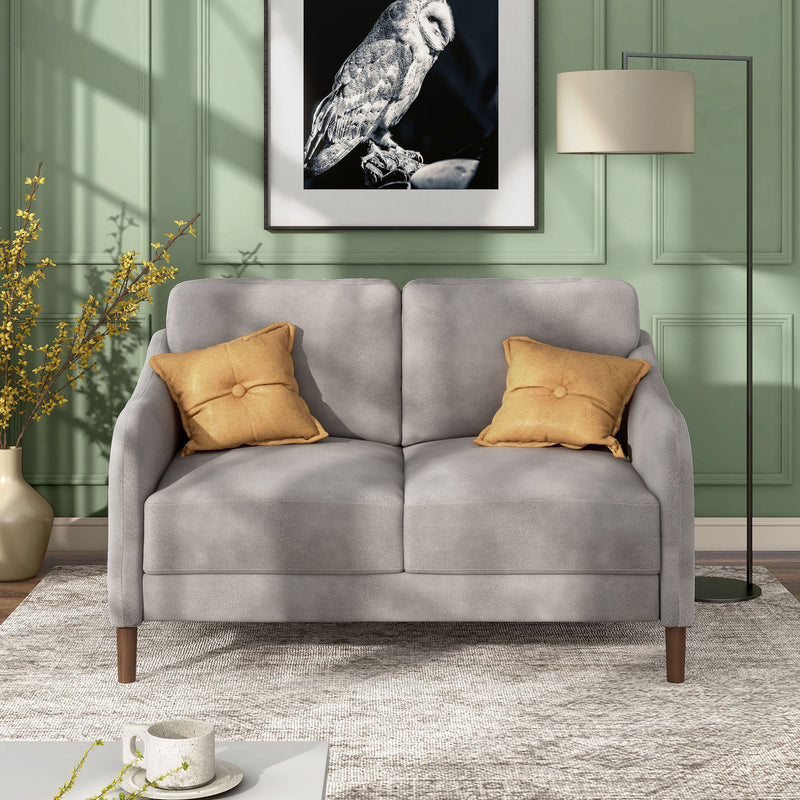 Front facing modern grey velvet loveseat with sloping arms in a room with accessories