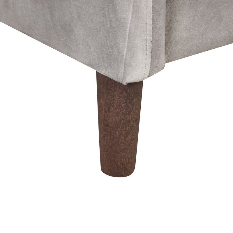 Right facing close up of the armrest on a modern grey velvet loveseat with sloping arms on a white background