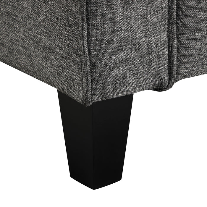 Right facing close up of the leg of a transitional grey linen-look accent armchair on a white background