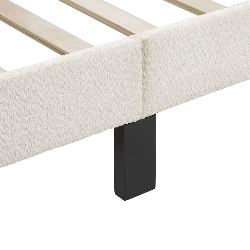 Left facing close up of the side rail, slats, and support leg of a modern white boucle upholstered queen bed on a white background