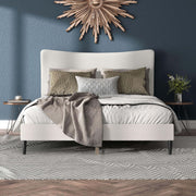 Front facing modern white boucle upholstered queen bed in a room with linens and accessories