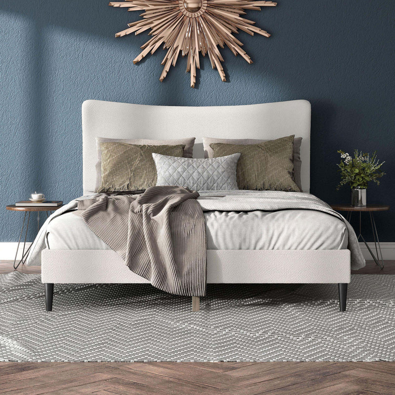 Front facing modern white boucle upholstered queen bed in a room with linens and accessories