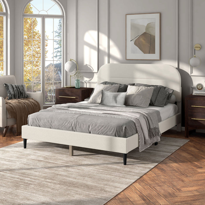 Left facing modern white boucle upholstered queen bed in a room with linens and accessories