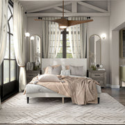 Front facing modern white boucle upholstered queen bed in a room with linens and accessories