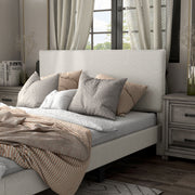 Left facing close up view of a modern white boucle upholstered queen bed in a room with linens and accessories