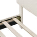 Left facing close up of the interior side rail, slats, and headboard of a modern white boucle upholstered queen bed on a white background