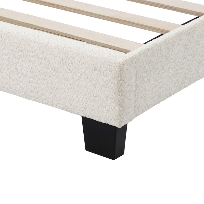 Left facing close up of the footboard corner and support leg of a modern white boucle upholstered queen bed on a white background