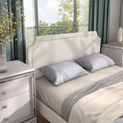 Right facing close up view of a modern white boucle upholstered queen bed in a room with linens and accessories