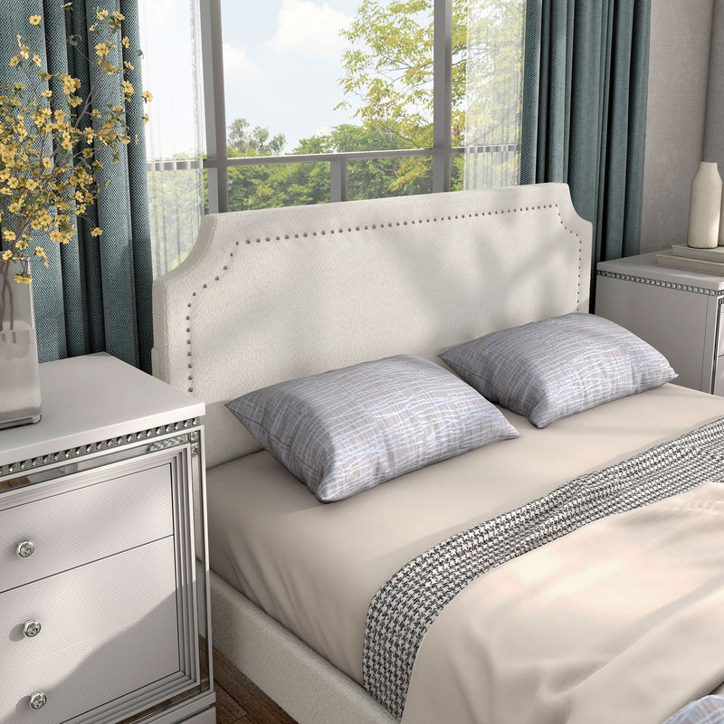 Right facing close up view of a modern white boucle upholstered queen bed in a room with linens and accessories