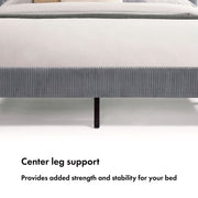 Front facing close up of the center leg support of a modern gray velvet textured headboard full platform bed on a white background
