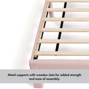 Left facing close up of the metal support and wooden slats of a modern gray velvet textured headboard full platform bed on a white background