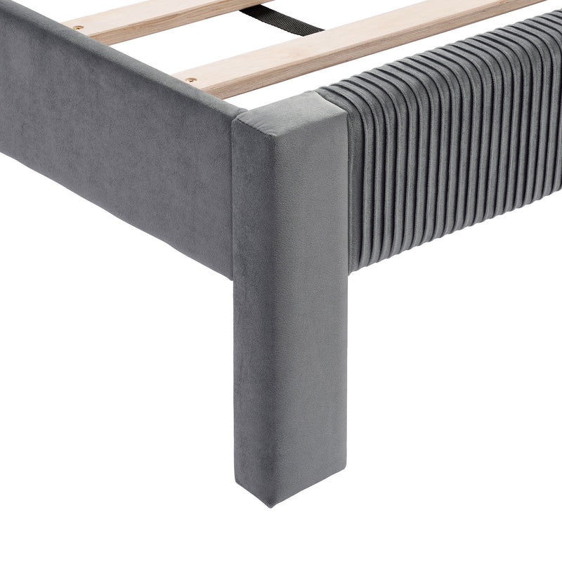 Right facing close up view of the footboard corner and slats on a modern gray velvet textured headboard queen platform bed on a white background