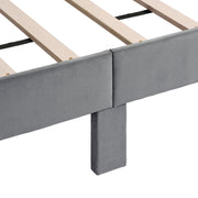 Right facing close up view of the support leg and slats on a modern gray velvet textured headboard queen platform bed on a white background
