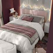 Left facing high-camera view of a modern pink velvet textured headboard queen platform bed in a room with linens and accessories