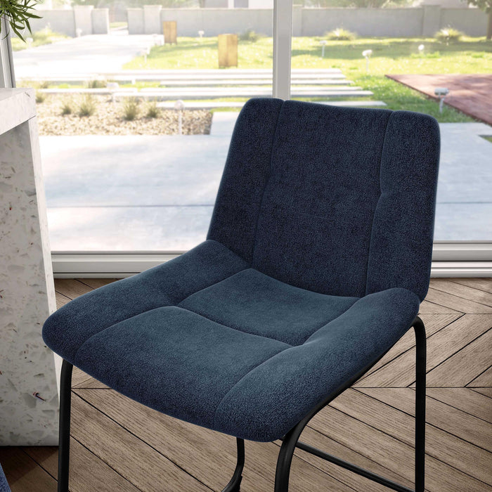 Left facing close up single view of a set of two contemporary blue chenille counter height stools with black bases in a room with accessories