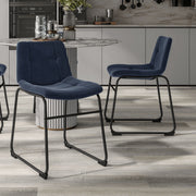 Angled set of two contemporary blue chenille dining side chairs with black bases in a room with accessories
