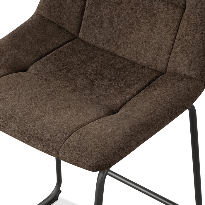 Left facing close up single view of a set of two contemporary brown chenille counter height stools with black bases in a room with accessories