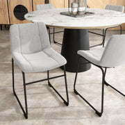 Angled set of two contemporary light grey chenille dining side chairs with black bases in a room with accessories