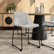 Angled set of two contemporary light grey chenille dining side chairs with black bases in a room with accessories