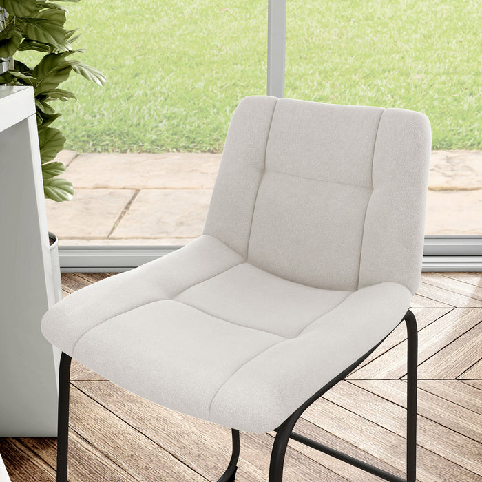 Left facing close up single view of a set of two contemporary white chenille counter height stools with black bases in a room with accessories