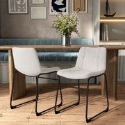 Angled set of two contemporary white chenille dining side chairs with black bases in a room with accessories