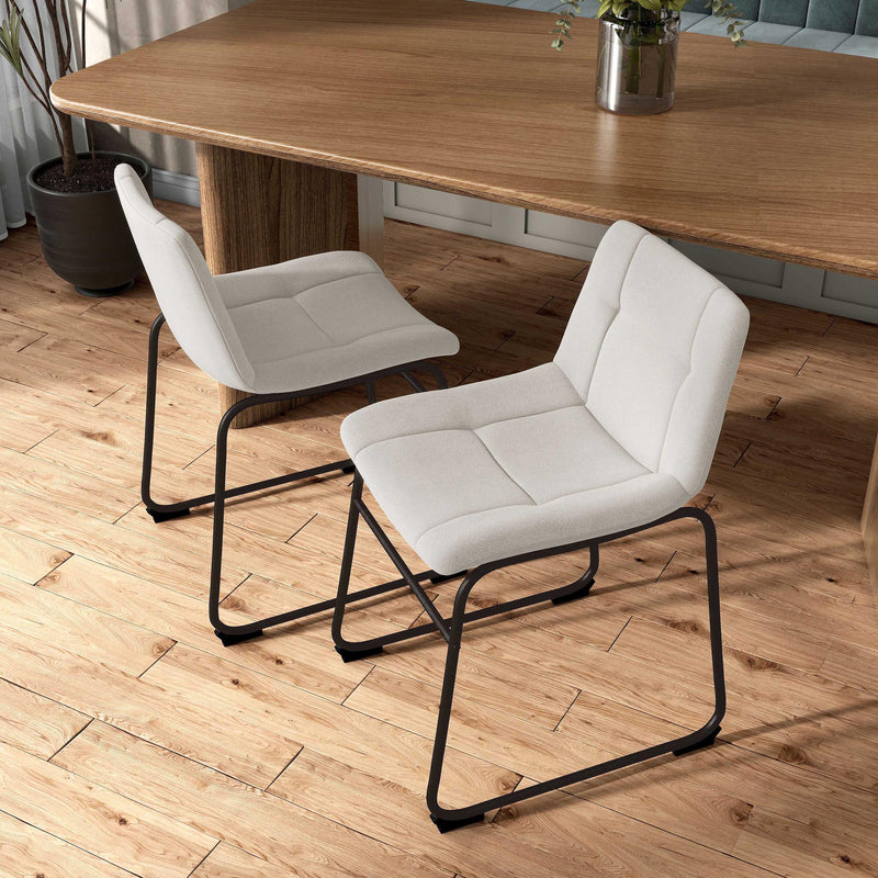 Angled set of two contemporary white chenille dining side chairs with black bases in a room with accessories