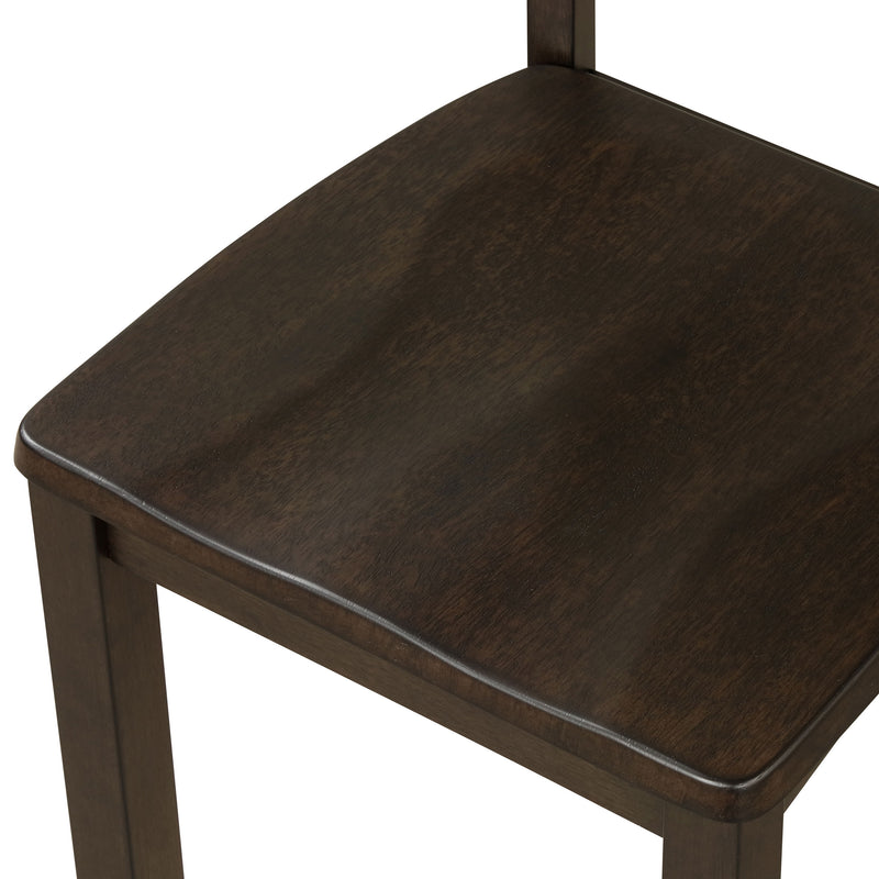 Left-facing close up of the contoured seat of the side chair featured in a five-piece traditional espresso wooden dining set with a table and four chairs on a white background