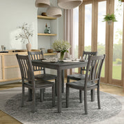 Side facing five-piece traditional grey wooden dining set with a table and four chairs on a white background
