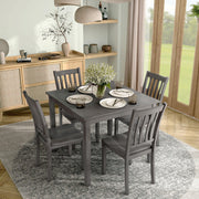 Side facing five-piece traditional grey wooden dining set with a table and four chairs on a white background