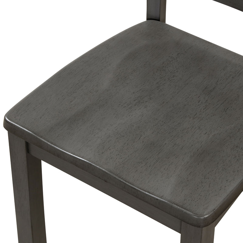 Left-facing close up of the contoured seat of the side chair featured in a five-piece traditional grey wooden dining set with a table and four chairs on a white background