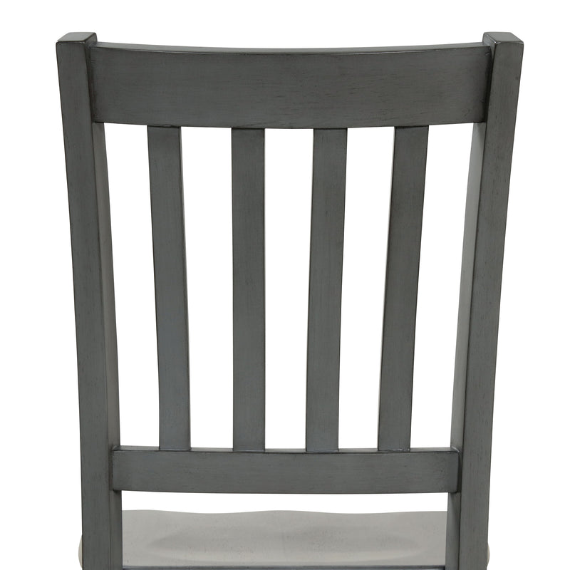 Front-facing close up of the slatted back of the side chair featured in a five-piece traditional grey wooden dining set with a table and four chairs on a white background