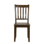 Front facing chair-only view of five-piece traditional walnut wooden dining set with a table and four chairs on a white background