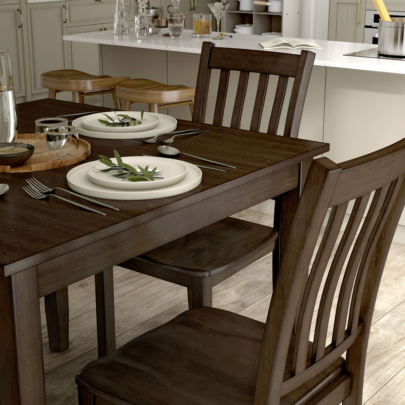Side facing close up view of a five-piece traditional walnut wooden dining set with a table and four chairs in a room with accessories
