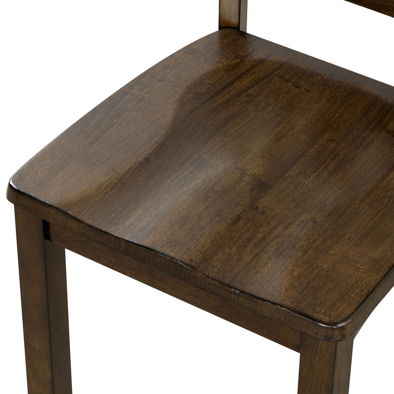 Left-facing close up of the contoured seat of the side chair featured in a five-piece traditional walnut wooden dining set with a table and four chairs on a white background