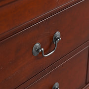 Right facing close up of a traditional cherry finish solid wood five-drawer chest showing its hanging drawer pulls