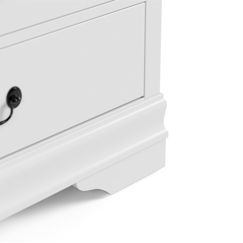 Right facing close up of a traditional white finish solid wood six-drawer dresser showing its lower molded trim and bracket foot, on a white background