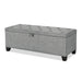 Left facing modern grey upholstered storage bench with a lift top on a white background