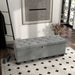Right facing modern grey upholstered storage bench with a lift top in a room with accessories
