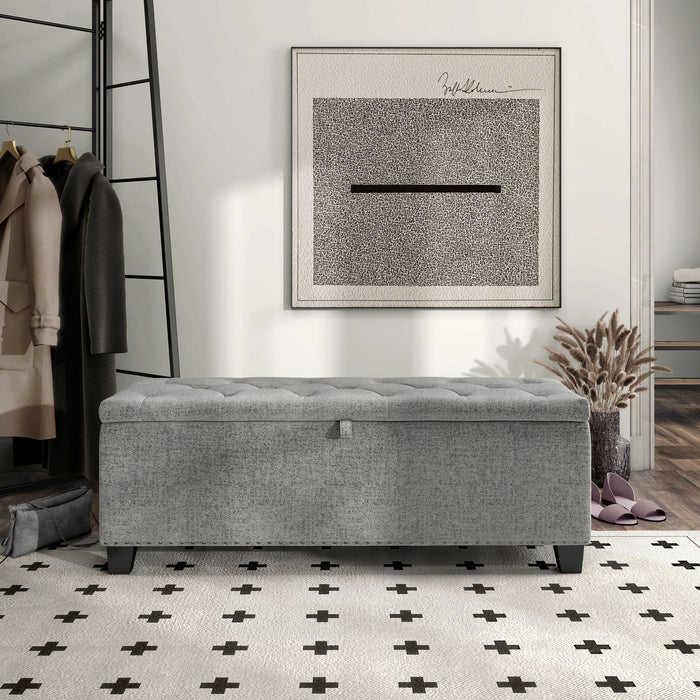 Front facing modern grey upholstered storage bench with a lift top in a room with accessories