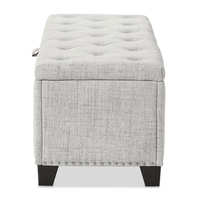 Front facing side view of a modern off white upholstered storage bench with a lift top on a white background
